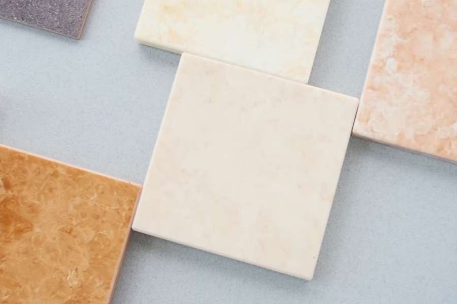 Échantillons de carrelage de différentes couleurs et textures disposés sur un fond gris clair pour choisir avant de poser du carrelage.