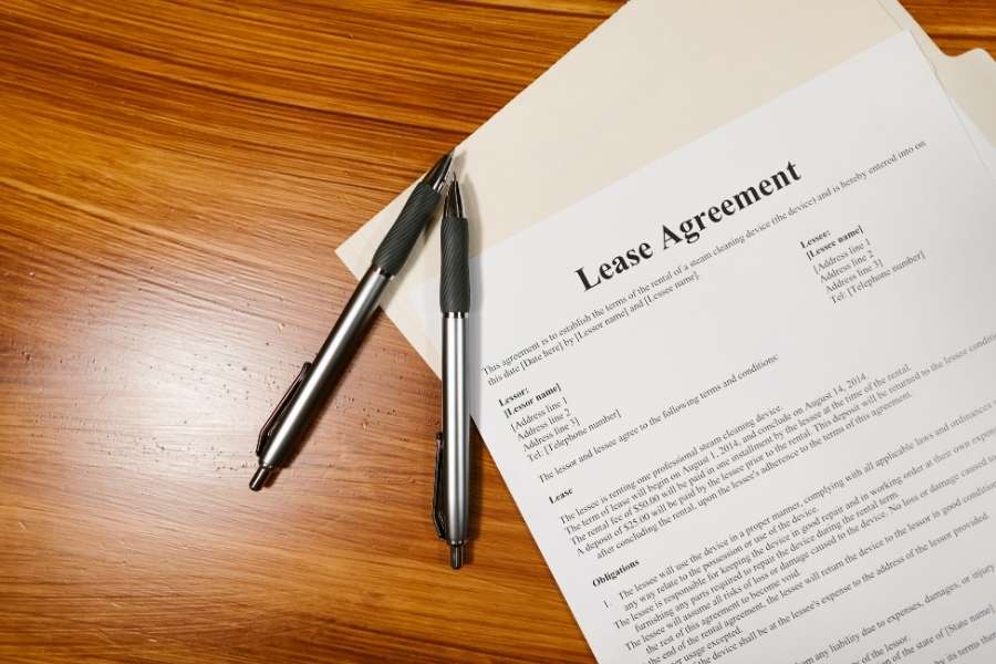 Un document de contrat de location prêt pour la signature d'un bail posé sur une table en bois avec deux stylos.