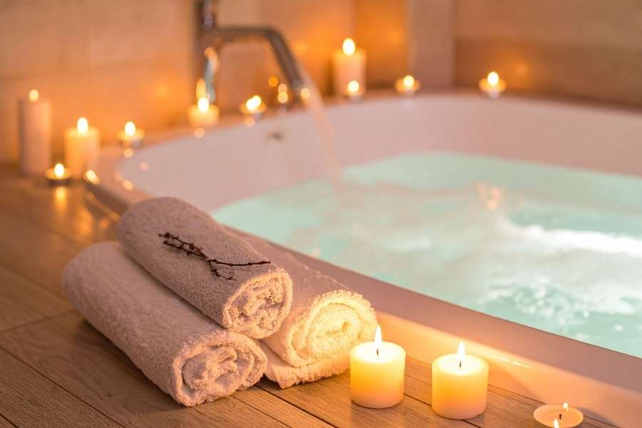 Ambiance relaxante avec des bougies autour d'une baignoire pour une salle de bain en spa privé.