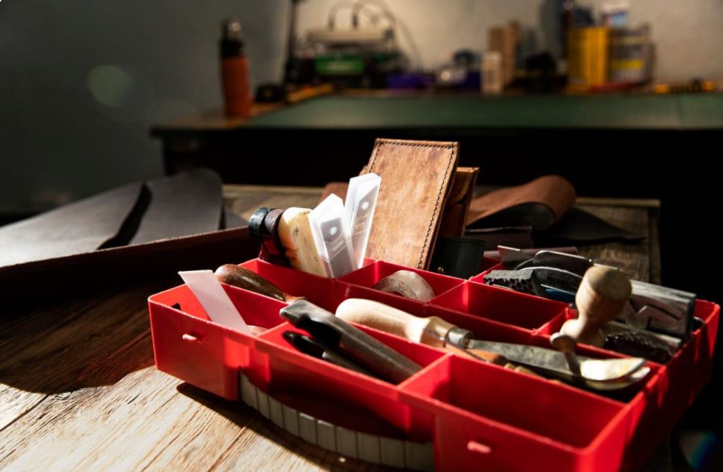 Boîte à compartiments rouge remplie d'outils et de pièces pour réussir ses travaux de plomberie soi meme