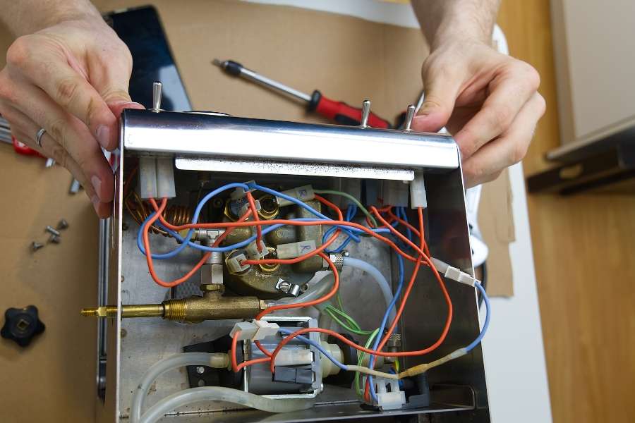 Un technicien en train de réparer ses appareils en manipulant les câbles internes d'une machine.