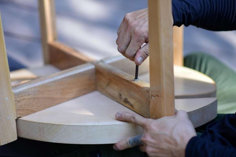 Un artisan utilise une clé Allen pour assembler ou restaurer un vieux meuble en bois clair
