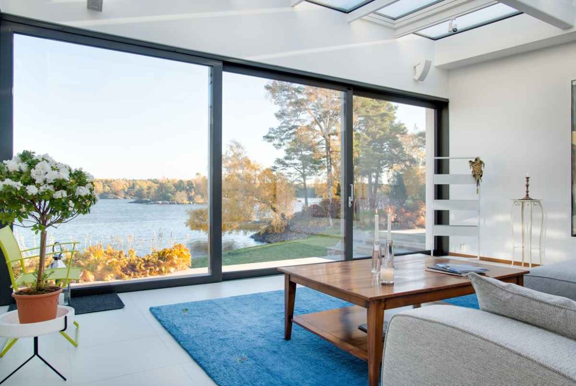 Grand salon moderne baigné de lumière avec une menuiserie pvc sur mesure prix pas cher ouvrant sur un paysage extérieur.