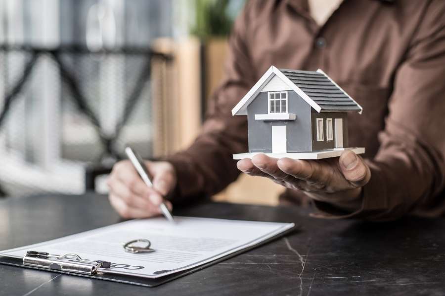 Une personne tient une maquette de maison pour estimer la valeur d'une maison